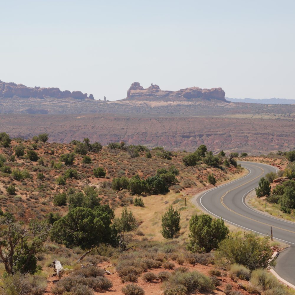 Un van aménagé stationné le long d’une route désertique australienne, entourée de vastes paysages rouges.