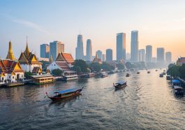 Vue immersive de Bangkok au lever du jour, avec des bateaux sur le fleuve Chao Phraya, des temples dorés et une skyline moderne.